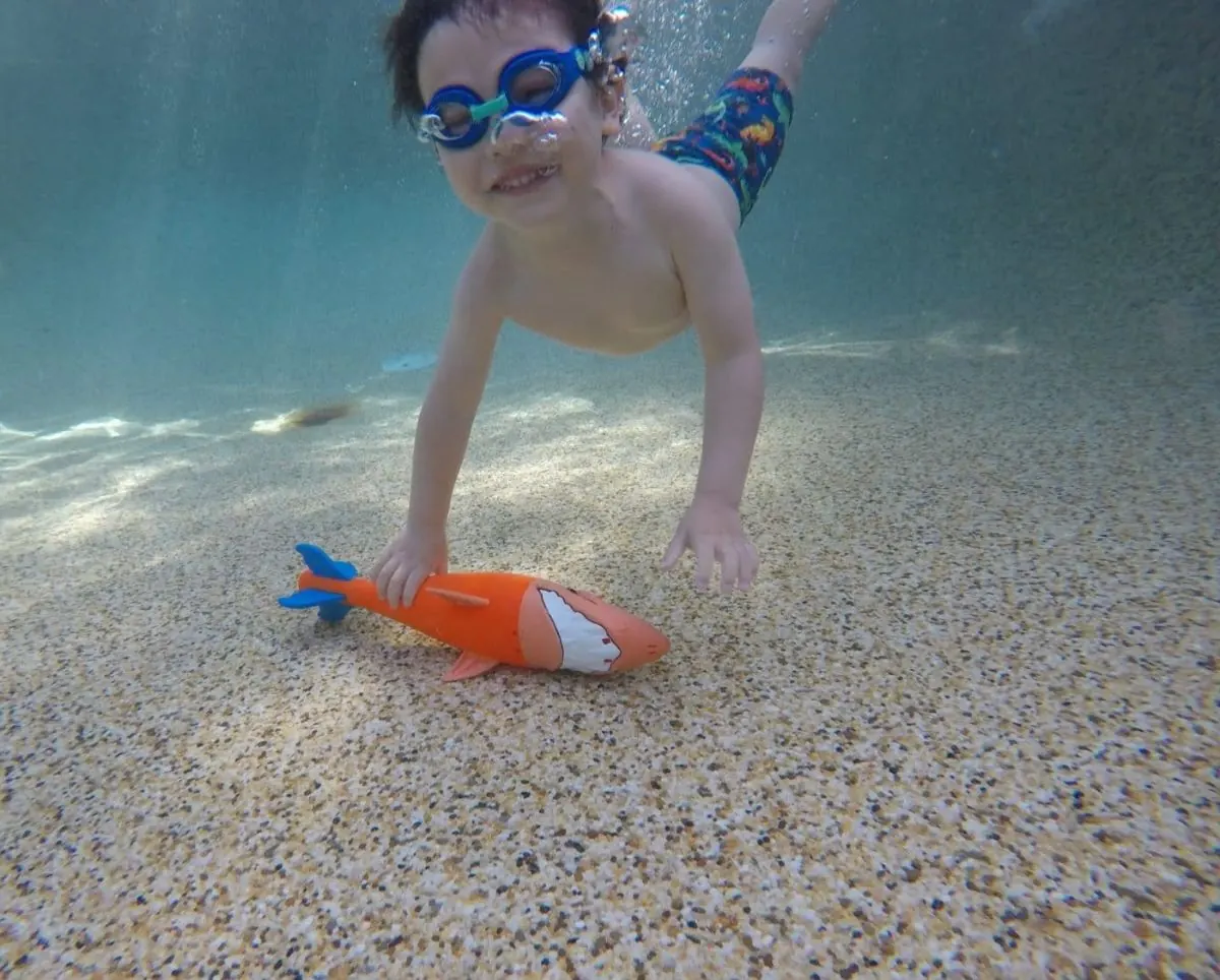 Child swimming underwater to collect a toy