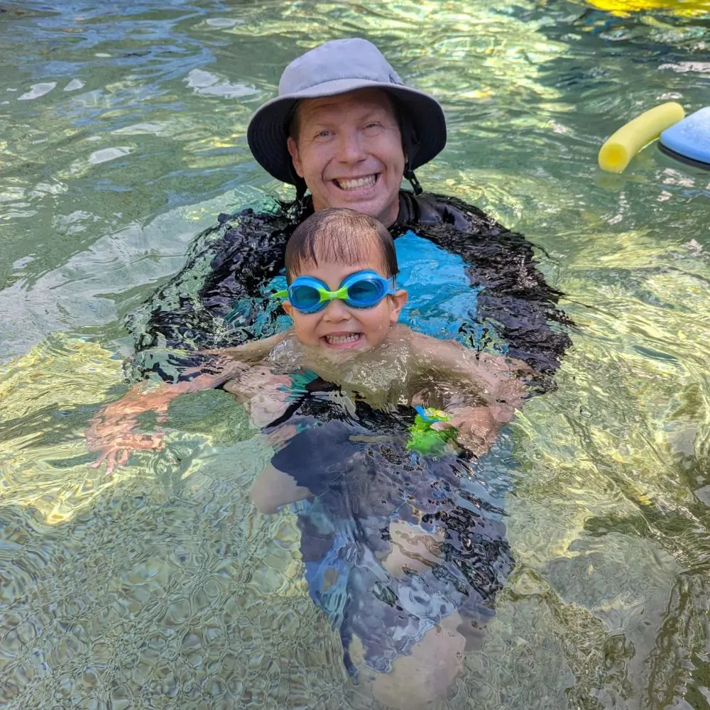 Coach in the water with a swimmer, both smiling