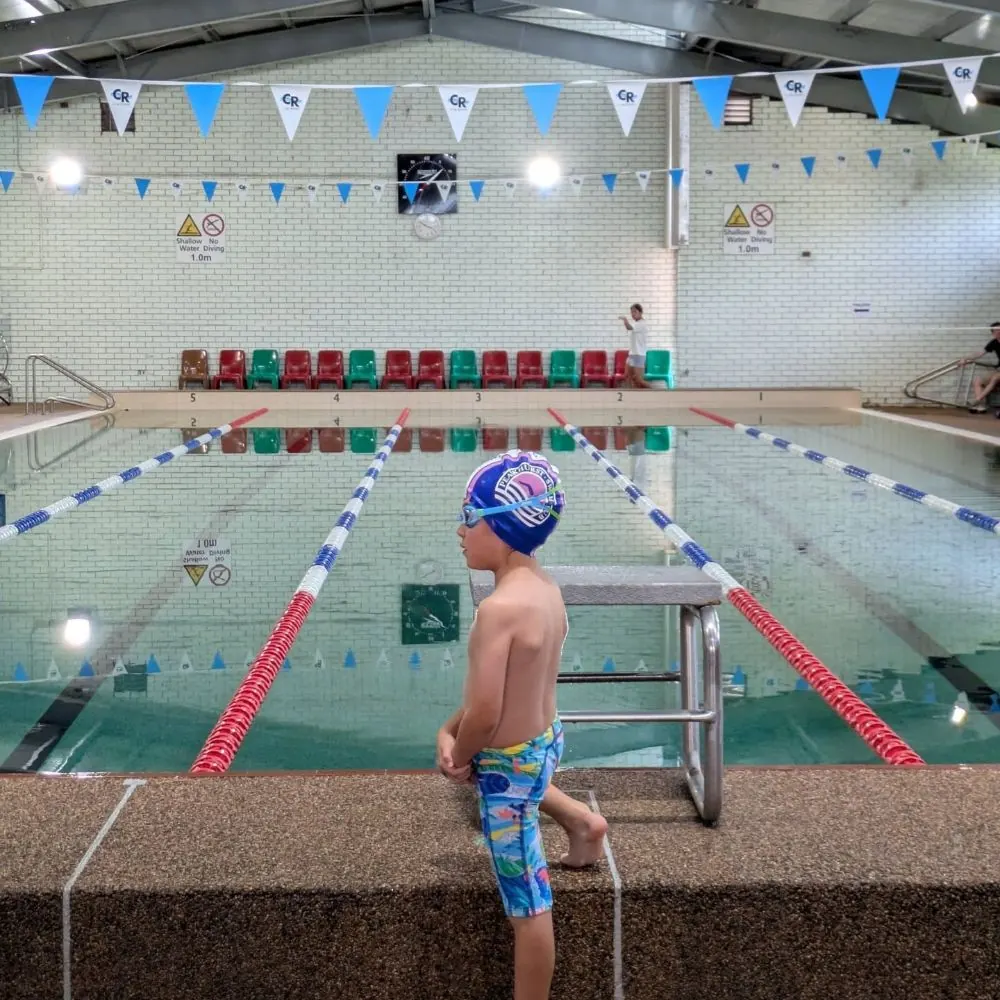 Young swimmer on the blocks at an indoor pool